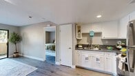 Located in Fontana, CA, this single-story home offers four bedrooms, one bathroom, and a thoughtfully arranged floor plan that maximizes every square foot. The kitchen is a standout feature, showcasing white shaker cabinetry, dark countertops, stainless steel appliances including a refrigerator, range, and built-in microwave, and a stainless steel sink. Light wood-style vinyl flooring runs throughout, lending a clean, cohesive look across the kitchen and adjacent living area. Recessed lighting and a textured ceiling add character to the main living space, which flows openly from the kitchen. The bedrooms are bright and functional, each featuring windows that allow natural light and views of outdoor greenery. The bathroom is appointed with white cabinetry, a dark countertop vanity, and a large mirror. Two closets provide additional storage, while a hallway connects the rooms efficiently. A patio extends the living space outdoors. Neutral warm-gray walls throughout create a calm, inviting atmosphere well-suited for comfortable everyday living.