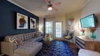 This single-story residence offers two bedrooms and two bathrooms across a thoughtfully designed floor plan. The living room serves as the focal point of the home, featuring a bold navy accent wall adorned with framed artwork, crown molding, a ceiling fan, and wood-look flooring throughout. Natural light filters in through large windows and a set of French doors that open to the outdoors. The kitchen is well-equipped with rich wood cabinetry, granite-style countertops, stainless steel appliances, a breakfast bar with seating, pendant lighting, and an in-unit washer and dryer. Both bedrooms are carpeted and feature ceiling fans, with one room showcasing a teal accent wall and ample natural light from dual windows. The two bathrooms differ in configuration — one includes a walk-in shower with sliding glass doors and wood-look flooring, while the second features a soaking tub with shower combination and a window for natural light. Both bathrooms include wood cabinetry and generous countertop space, completing this cohesive and inviting home.