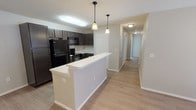 This single-floor residence offers a thoughtfully designed layout that balances functionality and comfort throughout. The kitchen serves as a central highlight, featuring dark espresso cabinetry, black appliances including a full-size refrigerator and electric range, and a spacious white peninsula breakfast bar that anchors the space. Dual pendant lights hang above the bar, adding a warm, modern touch, while a hallway leads seamlessly to the private living areas beyond.

The bedrooms are well-proportioned, each finished with light wood-style luxury vinyl plank flooring, neutral-toned walls, and ceiling fans with integrated lighting. Natural light filters in through blinded windows, contributing to a bright and airy atmosphere throughout. One bedroom includes access to a walk-in closet, providing practical storage.

The bathrooms are clean and functional, each equipped with a full tub-shower combination featuring white tile surrounds, chrome fixtures, and recessed lighting. The consistent use of light flooring and neutral wall tones ties the space together cohesively. Overall, this residence presents a modern, move-in-ready interior with a neutral palette that offers a versatile foundation for personalization.
