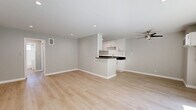 Located at 909 Palm Ave in the heart of West Hollywood, this thoughtfully updated one-bedroom, one-bathroom unit offers a clean, modern aesthetic throughout its efficiently designed single-floor layout. Light wood laminate flooring flows seamlessly through every room, complementing the neutral gray walls and crisp white trim that give the space a bright, contemporary feel.

The open-concept living and kitchen area serves as the heart of the unit. The kitchen is well-appointed with white shaker cabinetry, dark stone countertops, stainless steel appliances, and a peninsula with bar seating that connects to the living area. Recessed lighting and a ceiling fan ensure the space is comfortable and well-lit. A sliding glass door in the living room opens to a private balcony with a metal mesh railing, offering views of palm tree-lined streets characteristic of the West Hollywood neighborhood.

The generously sized primary bedroom features its own sliding glass door to the balcony, a ceiling fan, and mirrored sliding closet doors that enhance the sense of space and reflect natural light. The bathroom is finished in clean white tile and includes a full soaking tub with a window above for natural ventilation. A dedicated hallway connects the rooms, adding functional flow to the layout.