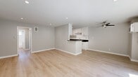 Located at 909 Palm Ave in the heart of West Hollywood, this thoughtfully updated one-bedroom, one-bathroom unit offers a clean, modern aesthetic throughout its efficiently designed single-floor layout. Light wood laminate flooring flows seamlessly through every room, complementing the neutral gray walls and crisp white trim that give the space a bright, contemporary feel.

The open-concept living and kitchen area serves as the heart of the unit. The kitchen is well-appointed with white shaker cabinetry, dark stone countertops, stainless steel appliances, and a peninsula with bar seating that connects to the living area. Recessed lighting and a ceiling fan ensure the space is comfortable and well-lit. A sliding glass door in the living room opens to a private balcony with a metal mesh railing, offering views of palm tree-lined streets characteristic of the West Hollywood neighborhood.

The generously sized primary bedroom features its own sliding glass door to the balcony, a ceiling fan, and mirrored sliding closet doors that enhance the sense of space and reflect natural light. The bathroom is finished in clean white tile and includes a full soaking tub with a window above for natural ventilation. A dedicated hallway connects the rooms, adding functional flow to the layout.
