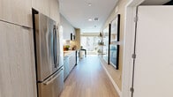 Located at 110 Constitution Dr in Menlo Park, CA, this thoughtfully designed one-bedroom, one-bathroom residence offers a efficient and stylish single-floor layout. Light wood-tone flooring flows throughout, unifying the space with a warm, contemporary aesthetic.

The galley-style kitchen is well-appointed with full stainless steel appliances — including a French door refrigerator, electric range, built-in microwave, and dishwasher — complemented by sleek light-toned cabinetry, a white subway tile backsplash, and ample counter space. Open shelving along one wall adds both functionality and visual interest.

The living room is bathed in natural light through large windows, offering pleasant outdoor views and an inviting, airy atmosphere. A dining area adjacent to the living space benefits from the same generous natural light, making it ideal for both relaxing and entertaining.

The bedroom features a striking geometric wood-panel accent wall that adds warmth and character, along with a frosted glass sliding closet door. The bathroom is finished with bold textured green tile, white subway tile in the shower, large-format floor tiles, and a modern vanity with wood cabinetry, delivering a refined and stylish look throughout.