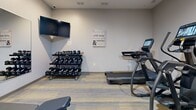 Located at 2945 Brick Church Pike in Nashville, Tennessee, this fitness center offers a well-equipped exercise space designed to support a well-rounded workout routine. The room features neutral gray walls, recessed lighting, and durable patterned carpet flooring with yellow and gray tones, creating a clean and functional environment.

The cardio section is equipped with multiple Matrix treadmills and an elliptical trainer, each outfitted with individual screens for entertainment during workouts. A Matrix multi-functional cable machine and an adjustable weight bench provide options for strength and resistance training. A tiered dumbbell rack holds a full range of free weights, catering to various fitness levels. A wall-mounted flat-screen television is positioned above the weight rack, adding to the room's utility.

A large wall mirror enhances the sense of space and allows users to monitor their form during exercise. A thermostat on the wall ensures climate comfort can be adjusted as needed. The room is accessed through a glass-paneled door, lending a modern, professional aesthetic to the entry. Motivational wall art adds an encouraging touch to the overall atmosphere. This fitness center is a practical and fully outfitted space for residents or guests seeking convenient access to exercise facilities.