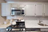 Located at the corner of Georgia Ave and Fenwick Lane in Silver Spring, MD, this well-appointed 2-bedroom, 3-bathroom residence offers a thoughtfully designed layout across a single floor. The living room is a standout space, featuring light wood-style flooring, large floor-to-ceiling windows that flood the room with natural light and provide open views of the surrounding cityscape, creating an airy and inviting atmosphere. The kitchen is outfitted with gray shaker-style cabinetry, white quartz countertops, a classic subway tile backsplash, and stainless steel appliances, combining both style and functionality. The generously sized primary bedroom features plush wall-to-wall carpeting, a large window with urban views, and multiple closets including a dedicated walk-in area, offering abundant storage. The second bedroom is equally well-proportioned with carpet flooring and space for both sleeping and a work area. Three bathrooms serve the residence, one of which features light wood-style flooring, gray vanity cabinetry with brushed gold hardware, and louvered closet doors. Throughout the home, a neutral color palette of soft whites and warm grays creates a calm, cohesive ambiance well-suited for comfortable everyday living.