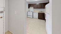 Located at 14795 NE 18th Ave in North Miami Beach, FL, this single-floor unit offers a clean, functional layout with consistent light beige tile flooring throughout every room. The open living area is bright and welcoming, featuring vertical blinds and a sliding glass door that invites natural light and provides views of the surrounding greenery. The kitchen is outfitted with dark espresso-toned cabinetry, light countertops, and white appliances including a range, dishwasher, and refrigerator, creating a practical and efficient cooking space. The bedrooms are generously proportioned, featuring neutral gray walls, tile flooring, and windows dressed with vertical blinds that allow for adjustable natural light. One bedroom includes access to a closet, adding functional storage. The unit includes two bathrooms: one featuring a full bathtub and shower combination with white tile surround, and a second with a standalone shower stall, both finished with clean white fixtures and tile flooring. Textured ceilings are present throughout, and the overall color palette of soft grays and whites gives the space a neutral, move-in-ready aesthetic well-suited for the South Florida lifestyle.