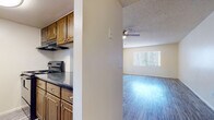 This single-story residence is thoughtfully laid out to maximize functionality and comfort. Entry is through a classic six-panel white door that opens into a hallway with wood-look luxury vinyl plank flooring, which flows consistently throughout the entire home, lending a cohesive and clean aesthetic.

The galley-style kitchen runs along two parallel walls, outfitted with warm-toned wooden cabinetry, dark granite-style countertops, a black refrigerator, an electric range, and an overhead exhaust hood. The efficient layout makes excellent use of the available space, with ample upper and lower cabinet storage.

The living area is open and well-lit, featuring a ceiling fan with a light fixture and a large window dressed with vertical blinds that invite natural light into the room. The textured popcorn ceiling adds a classic residential character throughout the space.

Two bedrooms offer comfortable proportions, each with windows fitted with vertical blinds, closet storage, and the same durable vinyl plank flooring. Neutral wall tones keep the rooms feeling bright and versatile.

Two bathrooms serve the residence, each featuring a vanity with dark countertops and wooden cabinetry. One bathroom includes a stand-up shower, while the other offers a full shower-tub combination, both finished with clean white surrounds and coordinating fixtures.