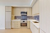 Located on the 8th floor at 1224 M St NW in Washington, DC, this modern one-bedroom residence offers a thoughtfully designed single-level layout. Light wood flooring runs throughout the unit, creating a cohesive and airy aesthetic complemented by soft, neutral wall tones.

The kitchen is a standout feature, showcasing flat-front light wood cabinetry extending to the ceiling for ample storage, white quartz countertops, and a sleek gray tile backsplash. Stainless steel Bosch appliances — including a gas range, wall oven, over-the-range microwave, and dishwasher — complete the space with a polished, contemporary finish.

The open dining and living area flows naturally from the kitchen, bathed in natural light from floor-to-ceiling windows that frame city views. The bedroom offers a comfortable footprint with direct access to a closet, an additional sliding-door closet, and an adjacent bathroom. The bathroom features marble-look tile flooring, a soaking tub with a full-height textured tile surround, and a wood-accented vanity.

A dedicated in-unit laundry closet with stacked Samsung washer and dryer adds everyday convenience. Three closets throughout the unit provide generous storage. The entrance leads efficiently into the living spaces, making this a well-organized and modern urban residence in the heart of Washington, DC.