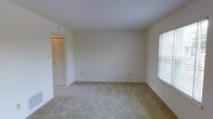This two-floor residence offers a straightforward and functional layout designed to maximize livable space. The interior is finished in a clean, neutral color palette throughout, with white walls and light-toned carpeting that create a bright and airy atmosphere. Natural light filters in through windows fitted with blinds, contributing to the open and welcoming feel of the rooms. The space observed features a generously sized carpeted room with smooth white ceilings, wall-mounted light switches, and standard electrical outlets positioned conveniently throughout. A bi-fold closet door provides practical storage access, hinting at thoughtful built-in storage solutions within the home. The minimalist, move-in-ready condition of the space allows for flexible interior design and personalization. The two-floor configuration provides a natural separation between living and private areas, offering both functionality and comfort. Overall, the residence presents a clean, well-maintained environment with a simple yet versatile design that serves as an excellent canvas for a new occupant to make their own.