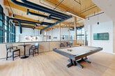 This contemporary 760 square foot space in Fairfax, VA, showcases a striking blend of industrial and modern design elements. The single-floor layout is characterized by its openness and versatility. High ceilings with exposed wooden beams and black ductwork create a loft-like atmosphere, while expansive windows flood the area with natural light.

The flooring throughout is a warm, light-toned hardwood, lending a cohesive feel to the various functional zones. A prominent feature is the bar area, with its sleek counter and high chairs, perfect for casual dining or socializing. Adjacent to this, comfortable lounge seating areas are arranged, featuring modern armchairs and sofas in neutral tones.

Built-in shelving units and cabinetry in light wood tones provide ample storage and display space, maintaining the clean, uncluttered aesthetic. The space also incorporates a recreational area, complete with what appears to be a pool table, further enhancing its multi-functional appeal.

Lighting is thoughtfully designed with a mix of recessed ceiling lights, pendant fixtures, and track lighting, allowing for adaptable illumination. The overall color palette of whites, light woods, and greys creates a bright, airy ambiance that complements the industrial elements.

This space efficiently combines work, play, and relaxation areas in a single, well-designed floor plan, making it suitable for a variety of uses from a modern office to a communal living area.