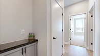 This well-appointed single-story home offers four bedrooms, two bathrooms, and a thoughtfully designed layout that maximizes functionality. The open kitchen and living area serves as the heart of the home, featuring gray shaker-style cabinetry with matte black hardware, dark granite countertops, a white subway tile backsplash, and a full suite of stainless steel Whirlpool appliances including a range, over-the-range microwave, and refrigerator. Light hardwood-style flooring flows throughout the main living areas, adding warmth and continuity. The living area is bathed in natural light through a large bank of windows fitted with roller shades, offering outdoor views and an airy, open feel. The four bedrooms are carpeted for comfort, with neutral tones and windows that bring in natural light. The primary bedroom includes its own closet. Both bathrooms are finished with gray-blue shaker vanities, white countertops, and matte black hardware. Three closets in total provide ample storage throughout. A dedicated laundry room houses a full-size Samsung washer and dryer. The home's clean, modern aesthetic is consistent across all rooms, creating a cohesive and move-in-ready living environment.