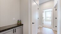 This well-appointed single-story home offers four bedrooms, two bathrooms, and a thoughtfully designed layout that maximizes functionality. The open kitchen and living area serves as the heart of the home, featuring gray shaker-style cabinetry with matte black hardware, dark granite countertops, a white subway tile backsplash, and a full suite of stainless steel Whirlpool appliances including a range, over-the-range microwave, and refrigerator. Light hardwood-style flooring flows throughout the main living areas, adding warmth and continuity. The living area is bathed in natural light through a large bank of windows fitted with roller shades, offering outdoor views and an airy, open feel. The four bedrooms are carpeted for comfort, with neutral tones and windows that bring in natural light. The primary bedroom includes its own closet. Both bathrooms are finished with gray-blue shaker vanities, white countertops, and matte black hardware. Three closets in total provide ample storage throughout. A dedicated laundry room houses a full-size Samsung washer and dryer. The home's clean, modern aesthetic is consistent across all rooms, creating a cohesive and move-in-ready living environment.