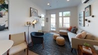This single-floor unit is thoughtfully laid out to maximize functionality and comfort. The open-concept living area serves as the heart of the space, featuring light wood-look flooring, recessed lighting, and large windows alongside a set of glass French doors that flood the room with natural light and provide access to an outdoor area. A wall-mounted mini-split system ensures year-round climate control. Floating shelves and clean white walls contribute to a bright, modern ambiance.

The kitchen is sleekly appointed with dark wood cabinetry extending to the ceiling, a classic white subway tile backsplash, light countertops, and a full suite of stainless steel appliances including a range, dishwasher, microwave, and refrigerator. A breakfast bar with seating connects the kitchen to the living area. Entry to the unit is through a distinctive frosted glass door.

The bedroom is a calm retreat with light wood flooring, a sliding closet, and a wall-mounted coat rack. The full bathroom features dark wood cabinetry, a wide vanity mirror, a tub-shower combination, and wood-look flooring, maintaining the cohesive contemporary aesthetic found throughout the space.