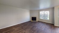 This two-floor residence at 1002 SW Campus Dr in Federal Way, Washington, offers a well-organized layout with functional living spaces distributed across both levels. The main living area is a focal point of the home, featuring rich, dark hardwood-style flooring, a tile-surround fireplace, and a textured ceiling. Natural light enters through a large window and a sliding glass door fitted with vertical blinds, which opens to a private patio offering views of surrounding greenery. A ceiling fan provides additional comfort in this open area.

The kitchen is equipped with white shaker-style cabinetry, light countertops, a deep double-basin stainless steel sink, and a stainless steel range, providing a clean and practical workspace. Hardwood-style flooring continues throughout the kitchen.

The bedrooms are carpeted and neutrally finished, with windows that bring in natural light. Baseboard heating is present in several rooms. The primary bedroom connects directly to a bathroom featuring white cabinetry, a vanity with a large mirror, and hardwood-style flooring. An additional full bathroom includes a shower with curtain, white vanity, and coordinating finishes. A dedicated in-unit laundry area houses a full-size washer and dryer with overhead wire shelving for storage.