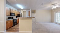 Located at 4000 Walden Way in Flowery Branch, Georgia, this single-story, three-bedroom, two-bathroom home offers a well-organized and functional layout. The open-concept kitchen and dining area serves as the heart of the home, featuring warm wood cabinetry, granite-style countertops, a breakfast bar peninsula, and black appliances including a range, dishwasher, and refrigerator. Hardwood-style flooring runs through the kitchen and flows into an adjacent nook area, while plush carpet carries through the living and bedroom spaces. The dining room is highlighted by elegant crown molding, a chair rail, and a classic chandelier, lending a refined touch to the space. The generously sized primary bedroom includes a ceiling fan and access to a walk-in closet outfitted with wire shelving on three walls for ample storage. The primary bathroom features a soaking tub with tiled surround. The secondary bathroom mirrors a clean, functional design with a single vanity, tub-shower combo, and tiled surround. Two additional carpeted bedrooms offer comfortable accommodations, each with easy closet access. A dedicated laundry room with hardwood-style flooring and wire shelving rounds out this well-appointed home.