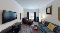 Located at 180 Embassy Dr in Fort Mill, SC, this single-floor residence offers a well-organized layout with distinct living, sleeping, and functional spaces. The living room is a welcoming area highlighted by crown molding, wood-look flooring, and natural light streaming through windows dressed with grommet-style curtains. A wall-mounted TV and comfortable seating arrangements make it an ideal gathering space.

The kitchen features white shaker-style cabinetry, granite-look countertops, and stainless steel appliances including a refrigerator, range, and over-the-range microwave. Wood-look flooring continues here, adding visual continuity throughout the home.

Multiple bedrooms provide comfortable accommodations, each carpeted for warmth and fitted with ceiling fans for climate control. Windows with grommet curtains allow natural light while maintaining privacy, and closet access is conveniently placed in each room.

The bathrooms are well-appointed with wood-look vinyl flooring, white vanity cabinetry, single-sink countertops with large mirrors, and shower-tub combinations. The clean, neutral palette throughout the home creates a cohesive and inviting atmosphere suited for everyday living in the Fort Mill community.