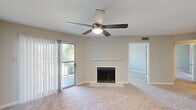 Located at 3214 Brassfield in Greensboro, NC, this 2-bedroom, 2-bathroom residence offers a well-organized single-floor layout designed for comfortable everyday living. The living room serves as the heart of the home, featuring a wood-burning fireplace with a classic white surround, plush wall-to-wall carpeting, and a ceiling fan with a light fixture. A sliding glass door framed by vertical blinds opens to a private balcony with outdoor views, filling the room with natural light. The kitchen is outfitted with white cabinetry, stainless steel appliances including a range, microwave, and refrigerator, and a peninsula with a light-toned countertop that provides additional prep and seating space. Light wood-style flooring runs throughout the kitchen, which connects openly to the living area. The bedrooms are carpeted and naturally lit through sizable windows with blinds. The primary bedroom is generously proportioned and includes access to a private bathroom featuring dark granite countertops, a tub-shower combination with tile surround, and wood-style flooring. A second full bathroom and a dedicated closet round out the layout. A hallway connects the rooms cohesively, and a textured ceiling finish is consistent throughout the home, adding a classic residential character.