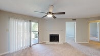 Located at 3214 Brassfield in Greensboro, NC, this 2-bedroom, 2-bathroom residence offers a well-organized single-floor layout designed for comfortable everyday living. The living room serves as the heart of the home, featuring a wood-burning fireplace with a classic white surround, plush wall-to-wall carpeting, and a ceiling fan with a light fixture. A sliding glass door framed by vertical blinds opens to a private balcony with outdoor views, filling the room with natural light. The kitchen is outfitted with white cabinetry, stainless steel appliances including a range, microwave, and refrigerator, and a peninsula with a light-toned countertop that provides additional prep and seating space. Light wood-style flooring runs throughout the kitchen, which connects openly to the living area. The bedrooms are carpeted and naturally lit through sizable windows with blinds. The primary bedroom is generously proportioned and includes access to a private bathroom featuring dark granite countertops, a tub-shower combination with tile surround, and wood-style flooring. A second full bathroom and a dedicated closet round out the layout. A hallway connects the rooms cohesively, and a textured ceiling finish is consistent throughout the home, adding a classic residential character.