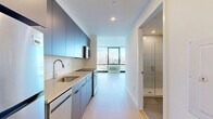 This 440 square foot studio apartment in Jersey City offers a thoughtfully designed living space that maximizes functionality without compromising on style. The open-plan layout seamlessly integrates the living area with the kitchen, creating a sense of spaciousness. Light wood flooring throughout adds warmth and continuity to the space.

The kitchen boasts modern stainless steel appliances and wooden cabinetry, providing ample storage and a contemporary aesthetic. The bathroom is a study in modern design, featuring a glass-enclosed shower, floating vanity, and large illuminated mirror.

A standout feature is the floor-to-ceiling windows that flood the space with natural light and offer breathtaking views of the Manhattan skyline. These windows not only create a visual connection to the urban landscape but also make the apartment feel larger than its actual square footage.

The apartment's clean lines, neutral color palette, and minimalist design contribute to a serene and uncluttered environment. Recessed lighting and strategically placed electrical outlets add to the overall functionality of the space. This studio is an excellent example of efficient urban living, perfect for those who appreciate a blend of form and function in a prime Jersey City location.