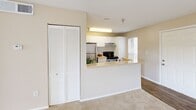 Located in Bradenton, Florida, this single-floor residence offers a thoughtfully designed layout that maximizes comfort and functionality. The kitchen serves as a central highlight, featuring stainless steel appliances including a refrigerator and range, white cabinetry with ample storage, wood-style flooring, and a peninsula countertop with a double sink — ideal for both cooking and casual dining. The open pass-through design connects the kitchen to the main living area, which is finished with plush wall-to-wall carpeting and neutral tones that create a warm, inviting atmosphere. A set of louvered bifold closet doors adds a classic touch near the living space.

The generously sized primary bedroom is carpeted and bathed in natural light from a large window, complemented by a ceiling fan for year-round comfort. It features direct access to a dedicated closet and an ensuite bathroom, which includes a vanity with mirror, sink, and a shower/tub combination. A private balcony extends the living space outdoors, offering a glimpse of the surrounding greenery — a welcome retreat in the Florida climate. Throughout the home, a soft, neutral color palette and clean finishes contribute to a bright, cohesive feel.