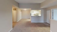 This single-floor residence offers a practical and comfortable layout designed for everyday living. The open-concept living area is finished with plush wall-to-wall carpeting and neutral gray tones, flowing seamlessly into the kitchen via a pass-through counter opening. The kitchen is well-appointed with white cabinetry, a full-size refrigerator, a stove, a sink, and light wood-style flooring, providing a clean and functional workspace. A closet adjacent to the living area adds convenient storage.

The residence includes two bedrooms, each carpeted and painted in soft neutral tones. Both rooms receive natural light through windows overlooking the surrounding neighborhood. One bedroom features dual closets, offering generous storage space, while the other provides ample room for comfortable furnishing.

Two full bathrooms serve the residence, each featuring a full-size soaking tub and shower combination with chrome fixtures, a toilet, and a wall-mounted mirror. One bathroom includes a vanity with a single sink and overhead lighting. Both bathrooms are finished with wood-style flooring, complementing the clean, neutral palette carried throughout the home.

Overall, the space presents a cohesive, move-in-ready environment with consistent finishes, practical storage solutions, and a functional floor plan suited for a variety of living arrangements.