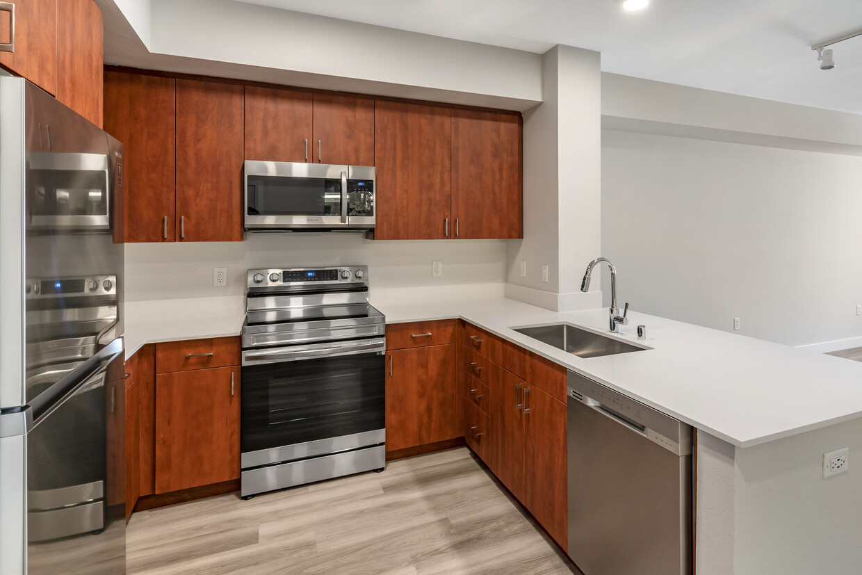 Renovated Package I kitchen with stainless steel appliances, white quartz countertops, cherry cabinetry, and hard surface flooring - Avalon Union City