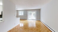 Located at 296 Grenfell St in Oshawa, Ontario, this single-floor, 2-bedroom, 1-bathroom unit offers a practical and well-appointed layout. The open kitchen and living area form the heart of the space, where white cabinetry, a classic subway tile backsplash, and a striking marble-style countertop with a double stainless steel sink set a clean, modern tone. Stainless steel appliances, including a refrigerator and electric range, complete the kitchen, which features white tile flooring. The living area extends naturally from the kitchen, filled with natural light from a large sliding glass patio door and an additional window, and is finished with warm, polished parquet flooring that runs throughout the space. Both bedrooms are comfortably sized, with the primary bedroom offering a generous footprint, neutral grey walls, and the same warm parquet flooring. Each room is serviced by baseboard heating. The bathroom is finished with classic white subway tile surrounding a full soaker tub and shower combination, lending a clean and timeless aesthetic. The overall color palette of soft greys and whites, paired with the warm wood-toned floors, creates a bright and cohesive living environment throughout the unit.