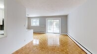 Located at 296 Grenfell St in Oshawa, Ontario, this single-floor, 2-bedroom, 1-bathroom unit offers a practical and well-appointed layout. The open kitchen and living area form the heart of the space, where white cabinetry, a classic subway tile backsplash, and a striking marble-style countertop with a double stainless steel sink set a clean, modern tone. Stainless steel appliances, including a refrigerator and electric range, complete the kitchen, which features white tile flooring. The living area extends naturally from the kitchen, filled with natural light from a large sliding glass patio door and an additional window, and is finished with warm, polished parquet flooring that runs throughout the space. Both bedrooms are comfortably sized, with the primary bedroom offering a generous footprint, neutral grey walls, and the same warm parquet flooring. Each room is serviced by baseboard heating. The bathroom is finished with classic white subway tile surrounding a full soaker tub and shower combination, lending a clean and timeless aesthetic. The overall color palette of soft greys and whites, paired with the warm wood-toned floors, creates a bright and cohesive living environment throughout the unit.