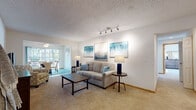 Located at 10902 75th St in Kenosha, Wisconsin, this single-floor residence offers a well-organized and comfortable layout ideal for everyday living. The living room is a welcoming focal point, featuring soft wall-to-wall carpeting, a textured ceiling, and a track lighting fixture that highlights the neutral walls. The open flow connects seamlessly to the dining area, which is finished with tile flooring, a ceiling fan with light, and a sliding glass door that fills the room with natural light and provides outdoor access. The kitchen is thoughtfully designed with rich, dark cabinetry, stainless steel appliances, recessed lighting, and a breakfast bar with seating — perfect for casual dining. The primary bedroom is generously sized, featuring carpet, a ceiling fan, and large windows that invite ample natural light. A second bedroom offers a bright and comfortable retreat with multiple windows and carpet flooring. The bathroom is well-appointed with a wide vanity, dark wood cabinetry, an extended countertop, a large wall mirror, and tile flooring. Throughout the residence, the consistent use of warm, neutral tones and carpeted living spaces creates a cohesive and inviting atmosphere.