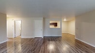 This single-floor unit offers a practical and well-organized layout across several distinct living areas. The main living space features rich, dark wood-look flooring that extends throughout, complemented by neutral-toned walls and clean white baseboards. A front entry area welcomes natural light through two large windows, creating a bright and open atmosphere. A pass-through window connects the living area to the kitchen, enhancing the sense of openness between spaces.

The galley-style kitchen is efficiently designed with dark espresso cabinetry lining both walls, white countertops, and matching white appliances including a range, refrigerator, and dishwasher. A dedicated door from the kitchen provides additional access and functionality.

Two bedrooms are finished with plush, neutral carpet and each includes a double-door closet offering generous storage. The rooms are well-proportioned with ample wall space and overhead ventilation.

Two bathrooms serve the unit. One features a stand-up shower with a framed glass door and tile flooring, while the second offers a full shower-tub combination, a single vanity with mirror, and matching tile flooring. Both bathrooms maintain a clean, functional aesthetic consistent with the rest of the unit.