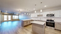 Located at 2620 W Sunshine St in Springfield, MO, this single-story, one-bedroom, two-bathroom home offers a thoughtfully designed open-concept layout with modern finishes throughout. The combined kitchen and living area serves as the heart of the home, featuring warm wood-look flooring, a ceiling fan, and natural light from a large window. The kitchen is well-appointed with crisp white upper cabinetry, two-toned lower cabinets, white quartz countertops, a subway tile backsplash, stainless steel appliances including a refrigerator, range, and microwave, and a spacious island with additional seating and storage. Pendant lighting adds a polished touch above the island. The generously sized bedroom features plush carpet flooring, a ceiling fan, and direct access to a full bathroom, providing a private and comfortable retreat. A walk-in closet with wire shelving offers ample storage. A dedicated laundry room houses a full-size washer and dryer with additional shelving. The pantry provides convenient extra storage. Neutral gray walls, recessed lighting, and clean white trim carry a cohesive, contemporary aesthetic throughout the entire home. An outdoor deck is also visible, extending the living space beyond the interior.