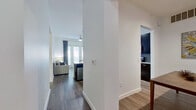 This single-floor, 2-bedroom, 3-bathroom residence offers a well-organized layout designed for comfortable, modern living. A central hallway connects the main living areas, creating a logical and flowing floor plan. The kitchen features dark espresso cabinetry, granite countertops, a mosaic tile backsplash, stainless steel appliances including a refrigerator, microwave, and range, and hardwood-style flooring — delivering both style and functionality. Adjacent to the kitchen, the dining area and open living room are filled with natural light from large windows and glass doors, complemented by hardwood-style flooring and a ceiling fan overhead. The primary bedroom is a generously sized retreat with plush carpeting, multiple windows with decorative curtains, a ceiling fan, and direct access to a private en-suite bathroom featuring dark wood cabinetry, granite countertops, and a tiled shower. The second bedroom is equally comfortable with soft carpeting and its own bathroom access. The three bathrooms throughout are consistently finished with granite vanity tops and dark wood cabinetry. A dedicated laundry room with a full-size washer and dryer adds everyday convenience, while two closets and a hallway provide ample storage across the residence.
