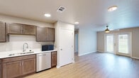 Located at 1409 Courtyard Dr SE in Bondurant, Iowa, this well-appointed one-bedroom, one-bathroom unit offers a thoughtfully designed single-floor layout. The open-concept kitchen is a standout feature, showcasing rich dark-stained cabinetry, white countertops, and a full suite of stainless steel appliances including a gas range, dishwasher, refrigerator, and microwave. Light wood-tone LVP flooring flows throughout the main living areas, creating a clean and cohesive aesthetic. The living room is bright and airy, enhanced by a ceiling fan and a glass patio door that invites natural light and opens to an outdoor view of green surroundings. The bedroom features plush carpeting, a ceiling fan, a window overlooking the outdoors, and a reach-in closet with built-in shelving for organized storage. The bathroom is well-equipped with a wide vanity, generous counter space, a large mirror, dark wood cabinetry including a tall linen tower, and LVP flooring. A dedicated laundry area houses a full-size Samsung front-loading washer and dryer with overhead shelving. The unit combines functional design with modern finishes, offering a comfortable and practical living space.
