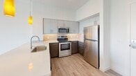 Located at 14 E Canal St in Richmond, Virginia, this single-floor unit offers a clean, modern aesthetic throughout its open layout. Light-toned hardwood-style flooring runs continuously through the main living areas and bedroom, creating a cohesive and visually spacious feel.

The kitchen is a standout feature, designed with a two-tone cabinet scheme pairing dark wood lower cabinets with light gray upper cabinets, all fitted with sleek bar-pull hardware. A herringbone-patterned tile backsplash adds visual interest behind the stainless steel appliances, which include a range, over-the-range microwave, and full-sized refrigerator. Light quartz countertops and a undermount sink complete the polished look, while pendant lighting overhead adds a warm accent.

The bedroom is bright and simply finished, with white walls, a ceiling fan with light fixture, and a built-in closet with a hanging rod. The room connects easily to the rest of the unit, offering a practical and comfortable layout.

The bathroom features light tile flooring, a dark wood vanity with a white countertop and undermount sink, a framed mirror with overhead lighting, and a full tub-shower combination. The all-white walls keep the space feeling clean and well-lit throughout.
