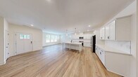 Located in Wake Forest, NC, this two-story home offers four bedrooms, four bathrooms, and a well-designed layout spread across two floors. The main floor presents an expansive open-concept living and kitchen area bathed in natural light from multiple windows. The kitchen is a standout feature, showcasing crisp white shaker cabinets, stainless steel appliances, a large center island with a built-in sink and seating, and elegant pendant lighting — all complemented by light hardwood flooring that flows seamlessly throughout the main level. The generous living room connects directly to the kitchen, creating an ideal space for entertaining. A clean, minimalist half bathroom is also located on the main floor, along with convenient garage access. The upper floor hosts all four bedrooms, including a spacious primary suite, along with the remaining bathrooms and a dedicated laundry room equipped with a full-size washer and dryer. Each bedroom features hardwood-style flooring, neutral tones, and windows with exterior views. Four closets provide ample storage throughout. The home's clean, modern aesthetic — defined by bright white walls, recessed lighting, and consistent finishes — creates a cohesive and welcoming atmosphere throughout.