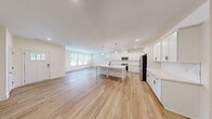 Located in Wake Forest, NC, this two-story home offers four bedrooms, four bathrooms, and a well-designed layout spread across two floors. The main floor presents an expansive open-concept living and kitchen area bathed in natural light from multiple windows. The kitchen is a standout feature, showcasing crisp white shaker cabinets, stainless steel appliances, a large center island with a built-in sink and seating, and elegant pendant lighting — all complemented by light hardwood flooring that flows seamlessly throughout the main level. The generous living room connects directly to the kitchen, creating an ideal space for entertaining. A clean, minimalist half bathroom is also located on the main floor, along with convenient garage access. The upper floor hosts all four bedrooms, including a spacious primary suite, along with the remaining bathrooms and a dedicated laundry room equipped with a full-size washer and dryer. Each bedroom features hardwood-style flooring, neutral tones, and windows with exterior views. Four closets provide ample storage throughout. The home's clean, modern aesthetic — defined by bright white walls, recessed lighting, and consistent finishes — creates a cohesive and welcoming atmosphere throughout.