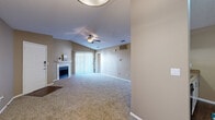 This single-story, 2-bedroom, 3-bathroom home offers a functional and comfortable layout across a well-utilized floor plan. The open-concept living and dining area is anchored by a fireplace and features plush carpeting, vaulted ceilings, a ceiling fan, and a sliding glass door that fills the space with natural light. The kitchen connects seamlessly to the living area via a pass-through counter and is equipped with white cabinetry, granite-style countertops, black appliances, and durable hardwood-style flooring. Both bedrooms are carpeted and include ceiling fans; the primary bedroom is generously sized with its own closet, while the second bedroom benefits from a large window with outdoor views. Three full bathrooms serve the home, each featuring tub-shower combinations with tile surrounds. A dedicated in-unit laundry room accommodates a full-size washer and dryer with wire shelving above for added storage. Two closets with wire shelving systems provide ample organization throughout the home. Neutral warm-toned walls and textured ceilings carry throughout, creating a cohesive and inviting atmosphere across every room.