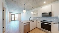 Located in the heart of Phoenix, this modern 2-bedroom, 2-bathroom residence at 50 E Fillmore St offers a well-designed urban living experience. The open-concept kitchen and living area serves as the centerpiece of the home, featuring an exposed concrete ceiling, light wood flooring, and a sleek kitchen island with quartz countertops and a matte black faucet. White cabinetry, a textured tile backsplash, and stainless steel appliances — including a refrigerator, range, microwave, and dishwasher — complete the kitchen. Globe pendant lights add a contemporary touch overhead. The living area flows seamlessly to a private balcony through floor-to-ceiling glass doors, offering sweeping views of the Phoenix skyline. Both bedrooms are bright and well-proportioned, with large windows that frame urban and city views, light wood flooring, and exposed concrete ceilings that add an industrial character. The primary bedroom includes a walk-in closet with built-in shelving and a dedicated bathroom featuring large-format floor tiles, floor-to-ceiling white wall tiles, a glass-enclosed shower, and dark wood vanity with matte black fixtures. A stacked in-unit washer and dryer with built-in shelving provides added convenience.
