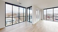 Located at 1711 Commonwealth Ave in Charlotte's vibrant Plaza Midwood neighborhood, this contemporary single-floor home offers 4 bedrooms, 3 bathrooms, and a thoughtfully designed open layout. Light-toned hardwood flooring flows throughout, complemented by crisp white walls and matte black accents that define the modern aesthetic.

The open-concept kitchen, dining, and living area serves as the heart of the home. The kitchen is appointed with striking quartz countertops featuring subtle veining, warm wood cabinetry, white upper cabinets, a herringbone tile backsplash, stainless steel appliances, and a large center island with an undermount sink. Dramatic black pendant lights hang overhead, adding bold contrast. Floor-to-ceiling black-framed windows flood the living area with natural light and offer sweeping views of the surrounding neighborhood.

The spacious primary bedroom continues the floor-to-ceiling window theme, providing abundant daylight and panoramic urban views, while a ceiling fan adds comfort. The primary bathroom features a double-sink vanity with quartz counters, matte black fixtures, a framed mirror, and a glass-enclosed shower. Additional bedrooms are well-sized with natural light and ceiling fans. Five closets—fitted with wire shelving systems—provide generous storage. A patio and two hallways round out this well-appointed home.