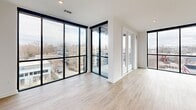 Located at 1711 Commonwealth Ave in Charlotte's vibrant Plaza Midwood neighborhood, this contemporary single-floor home offers 4 bedrooms, 3 bathrooms, and a thoughtfully designed open layout. Light-toned hardwood flooring flows throughout, complemented by crisp white walls and matte black accents that define the modern aesthetic.

The open-concept kitchen, dining, and living area serves as the heart of the home. The kitchen is appointed with striking quartz countertops featuring subtle veining, warm wood cabinetry, white upper cabinets, a herringbone tile backsplash, stainless steel appliances, and a large center island with an undermount sink. Dramatic black pendant lights hang overhead, adding bold contrast. Floor-to-ceiling black-framed windows flood the living area with natural light and offer sweeping views of the surrounding neighborhood.

The spacious primary bedroom continues the floor-to-ceiling window theme, providing abundant daylight and panoramic urban views, while a ceiling fan adds comfort. The primary bathroom features a double-sink vanity with quartz counters, matte black fixtures, a framed mirror, and a glass-enclosed shower. Additional bedrooms are well-sized with natural light and ceiling fans. Five closets—fitted with wire shelving systems—provide generous storage. A patio and two hallways round out this well-appointed home.