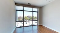 This single-floor unit combines modern design with functional living spaces, offering a bright and contemporary aesthetic throughout. The living area is a standout feature, defined by expansive floor-to-ceiling windows framed in dark metal that flood the space with natural light and provide elevated views of the surrounding urban streetscape, including tree-lined streets and neighboring brick buildings. Rich hardwood flooring extends through the main living and kitchen areas, adding warmth to the otherwise clean, neutral palette.

The kitchen is well-appointed with dark espresso cabinetry, granite countertops, and a full suite of stainless steel appliances, including a refrigerator, electric range, built-in microwave, and dishwasher. A peninsula counter connects the kitchen to the open living area, enhancing the overall flow of the space.

The bedrooms feature plush wall-to-wall carpeting and neutral tones, with one room benefiting from a large window overlooking treetops and city rooftops. A full bathroom includes tile flooring, a glass-enclosed shower, a dark wood vanity, and recessed lighting. A separate half bath features a pedestal sink and framed mirror, ideal for guests. Overall, the unit presents a cohesive, modern urban living environment.