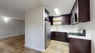 Located at 6710 Hayvenhurst Ave in Los Angeles, CA, this 2-bedroom, 1-bathroom unit is thoughtfully laid out across a single floor, offering a comfortable and functional living space. Light wood-tone flooring runs throughout, lending a clean, cohesive feel to every room. The living room is bright and open, featuring a window with natural light, a wall-mounted A/C unit, and a textured ceiling. It connects seamlessly to the kitchen area, which is equipped with rich dark-espresso cabinetry, white quartz countertops, open wood shelving, a stainless steel undermount sink with a modern pull-down faucet, and a full suite of stainless steel appliances including a gas range, microwave, and refrigerator. A skylight overhead adds natural brightness to the kitchen. The living area also features a generous wall of built-in white storage cabinetry. Both bedrooms continue the wood flooring and neutral tones, with the primary bedroom offering mirrored sliding closet doors and a window allowing natural light. The bathroom is clean and modern, featuring dark wood vanity cabinetry, a white quartz countertop, a framed mirror, and a tub-shower combination with white tile surround.