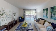 This single-floor residence offers a practical and comfortable layout with distinct living spaces connected by a clean, neutral design palette. The living room serves as the heart of the home, featuring plush carpeting, a textured ceiling, and a large sliding glass door that opens to a private balcony, flooding the space with natural light and providing views of surrounding greenery.

The galley-style kitchen is efficiently arranged with warm wood cabinetry lining both sides, white appliances including a coil-top range and refrigerator, light tile flooring, and a double stainless steel sink positioned beneath upper storage cabinets.

The primary bedroom is generously sized with soft carpet, two windows that invite natural light and tree-lined views, and a textured ceiling. It is complemented by a full bathroom featuring mosaic tile flooring, a vanity with wood cabinetry, a large mirror, a wall-mounted shelf, and a shower-tub combination.

A second bedroom offers a versatile space with carpeting, white walls, and ample room for flexible furniture arrangements. A second full bathroom mirrors the first in style, with mosaic tile flooring, a wood vanity, wide mirror, and a shower-tub combination.

Overall, the residence presents a cohesive, light-filled atmosphere with consistent finishes throughout.