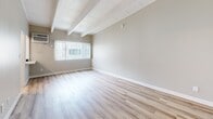 Located on Sherman Way in Los Angeles, CA, this thoughtfully designed 1-bedroom, 2-bathroom unit makes efficient use of its compact footprint. Light wood-tone flooring flows throughout, complementing a clean, modern aesthetic defined by crisp white walls and trim.

The kitchen is a standout feature, outfitted with white shaker cabinetry extending floor to ceiling, stainless steel appliances including a gas range, over-the-range microwave, and full-size refrigerator, plus a double undermount sink with quartz-style countertops. A window above the range brings in natural light, enhancing the bright, airy feel.

The combined dining and living area is open and luminous, highlighted by striking exposed beam ceilings and a large window that fills the space with ample natural light—adding architectural character and a sense of openness.

The primary bedroom offers a comfortable, private retreat with three closets providing generous storage. The two bathrooms are finished in a consistent white palette; one features a full vanity with white shaker cabinetry, a large mirror, and stylish lighting, while the second includes a full soaking tub with shower combination. Both bathrooms continue the light wood flooring for a cohesive look throughout the unit.