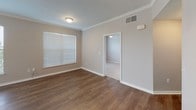 This single-floor residence offers a thoughtfully designed open-concept layout that seamlessly connects the living area and kitchen. The living space features warm hardwood-style flooring, crown molding, and track lighting, while large windows with blinds allow abundant natural light to fill the room. The kitchen is equipped with dark espresso cabinetry, granite countertops, black appliances including a range, over-the-range microwave, and refrigerator, along with a convenient peninsula that serves as a natural divider between the cooking and living areas. Light tile flooring carries throughout the kitchen.

The bedrooms are finished with plush wall-to-wall carpeting and feature windows that offer outdoor views. One bedroom includes a ceiling fan, while another opens directly onto a private balcony through sliding glass doors with vertical blinds. The space includes two bathrooms: a full bath with a tub-shower combination, dark vanity cabinetry, and tile flooring, and a second bath featuring a glass-enclosed walk-in shower and matching dark cabinetry. Crown molding accents the main living areas, contributing to a cohesive and polished aesthetic throughout the home.