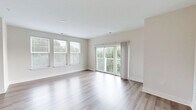 Located at 4705 Windsong Dr in Virginia Beach, Virginia, this well-appointed single-floor, 3-bedroom, 2-bathroom home offers a clean, modern aesthetic with a thoughtful layout. The open-concept kitchen is a standout feature, showcasing crisp white shaker cabinetry extending to the ceiling, a white quartz countertop with a large peninsula and double-basin sink, white subway tile backsplash, and a full suite of stainless steel appliances including a refrigerator, range, microwave, and dishwasher. Light wood-style flooring flows throughout the main living areas, complementing the bright, neutral color palette. The spacious living room receives generous natural light through large windows with outdoor views, and connects seamlessly to the kitchen. The primary bedroom includes a walk-in closet outfitted with multi-tiered wire shelving for ample storage. Additional bedrooms feature plush carpeting, natural light from windows, and built-in closets. Both bathrooms are finished with wood-style flooring, clean vanities, and chrome fixtures; one includes a walk-in shower with white tile surround and a grab bar. The overall ambiance is bright, fresh, and move-in ready.