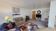 This single-floor home offers a practical and comfortable layout across several well-defined living spaces. The living room is generously sized, featuring soft carpeting, a textured ceiling, and room for multiple seating arrangements. A sliding glass door brings in natural light and connects the space to the outdoors, while a ceiling fan adds to the room's functionality. Adjacent to the living area is a dedicated dining space with room for a table and chairs, creating a natural flow for daily living.

The kitchen is efficiently designed with rich dark wood cabinetry that extends to the upper walls, providing ample storage. It includes a full suite of white appliances — refrigerator, electric range, and under-cabinet ventilation — along with tile flooring and a tiled backsplash.

The home includes multiple bedrooms, each carpeted and finished with textured ceilings. The primary bedroom features a window for natural light and a built-in closet with louvered doors and shelving. A secondary bedroom is thoughtfully appointed with a window, closet storage, and a bright, cheerful character. The full bathroom includes tile flooring, a vanity with storage, and a shower-tub combination with a curtain enclosure. Overall, the home presents a cozy and livable environment throughout.