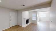 This single-floor residence offers a well-organized layout with a variety of functional spaces connected by a consistent design language of neutral tones and clean finishes throughout. The main living area is generously sized, featuring light hardwood-style flooring that runs throughout the common areas, textured ceilings, and a white-framed fireplace that serves as a focal point. A sliding glass door in the living room opens to an outdoor area and allows natural light to fill the space, complemented by multiple windows dressed with blinds. Exposed ceiling beams add a subtle architectural detail to the open-plan living and dining zones.

The kitchen is well-appointed with granite countertops, grey cabinetry, a classic white subway tile backsplash, and built-in appliances including a dishwasher. A peninsula counter provides a convenient transition between the kitchen and the adjacent dining or living area. The entryway welcomes residents with hardwood-style flooring and a built-in ledge detail along the wall.

The bedrooms offer plush carpeting, natural window light, and ample wall space, with one room featuring a built-in closet. Throughout the residence, the consistent use of white walls and neutral finishes creates a bright, cohesive atmosphere that is both practical and inviting.