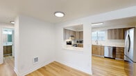 Located at 2909 NE 57th Ave in Vancouver, Washington, this single-floor, three-bedroom, one-bathroom home offers a clean, modern aesthetic throughout. Light hardwood flooring runs through the main living and kitchen areas, creating a bright and cohesive feel. The kitchen is a standout feature, designed with warm wood-tone cabinetry, crisp white countertops, and a full suite of stainless steel appliances including a French door refrigerator, electric range with oven, microwave, and dishwasher. A pass-through window connects the kitchen to the adjacent living area, enhancing the open feel of the space. The bedrooms are carpeted for comfort, with the primary bedroom offering a generous footprint and a spacious closet with built-in rods and shelving. Additional bedrooms are well-sized with neutral walls and windows that invite natural light and outdoor views. The bathroom is finished with a wood-tone vanity, white countertop, open shelving, and a full shower-tub combination. A dedicated laundry area includes a full-size side-by-side washer and dryer. The home's layout is efficiently organized, connecting all rooms through a central hallway for easy flow and accessibility.
