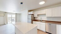 This 1-bedroom, 1-bathroom unit in Dilworth, Minnesota offers a thoughtfully designed layout that maximizes functionality and comfort. The open-concept kitchen and living area serves as the heart of the space, featuring crisp white cabinetry, warm wood-tone countertops, light luxury vinyl plank flooring, and a full suite of stainless steel appliances including a refrigerator, dishwasher, electric range, and microwave. A large central island with a clean white countertop provides additional prep space and casual seating. Pendant lighting above the island adds a modern touch. The living area extends to a sliding glass door that opens to a private balcony, allowing natural light to fill the room. The spacious bedroom offers plush carpeting, a ceiling fan with light fixture, a bright window with outdoor views, and baseboard heating. The bathroom is clean and functional, featuring a full soaking tub with shower surround. A dedicated in-unit laundry room comes equipped with a full-size Whirlpool washer and dryer, adding everyday convenience. Baseboard heating is present throughout, and the neutral color palette creates a bright, cohesive ambiance across the entire unit.