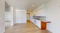 This thoughtfully designed 3-bedroom, 1-bathroom unit offers a clean, modern aesthetic throughout its single-floor layout. Light hardwood-style flooring flows continuously across every room, creating a cohesive and airy feel. The combined kitchen and living area serves as the heart of the unit, featuring a sleek galley-style kitchen outfitted with white flat-front cabinetry extending to the ceiling, a mosaic tile backsplash, neutral laminate countertops, and a full suite of white appliances including a range, built-in microwave, dishwasher, and refrigerator. A wall-mounted mini-split system provides efficient climate control in the living area. A dedicated laundry closet with stacked washer and dryer adds everyday convenience. The three bedrooms are bright and well-proportioned, each finished with crisp white walls and large windows that frame views of surrounding greenery and the urban skyline beyond. The primary bedroom offers a comfortable footprint with ample natural light. The full bathroom features a clean, minimalist design with a tub/shower combination and hardwood-style flooring. Throughout the unit, recessed lighting and a neutral color palette contribute to a fresh, move-in-ready atmosphere.